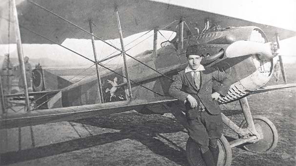 Vecihi Hürkuş in a flat cap, standing beside a biplane
